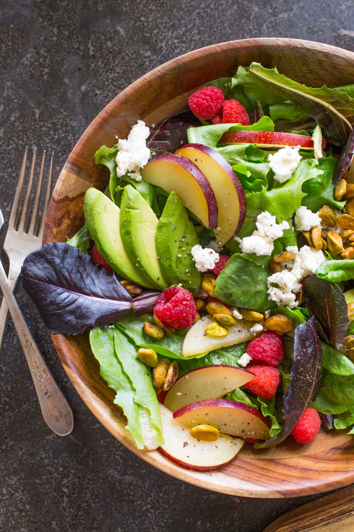 Summer Fruited Salad with Goat Cheese and Pistachios in a wood bowl.  