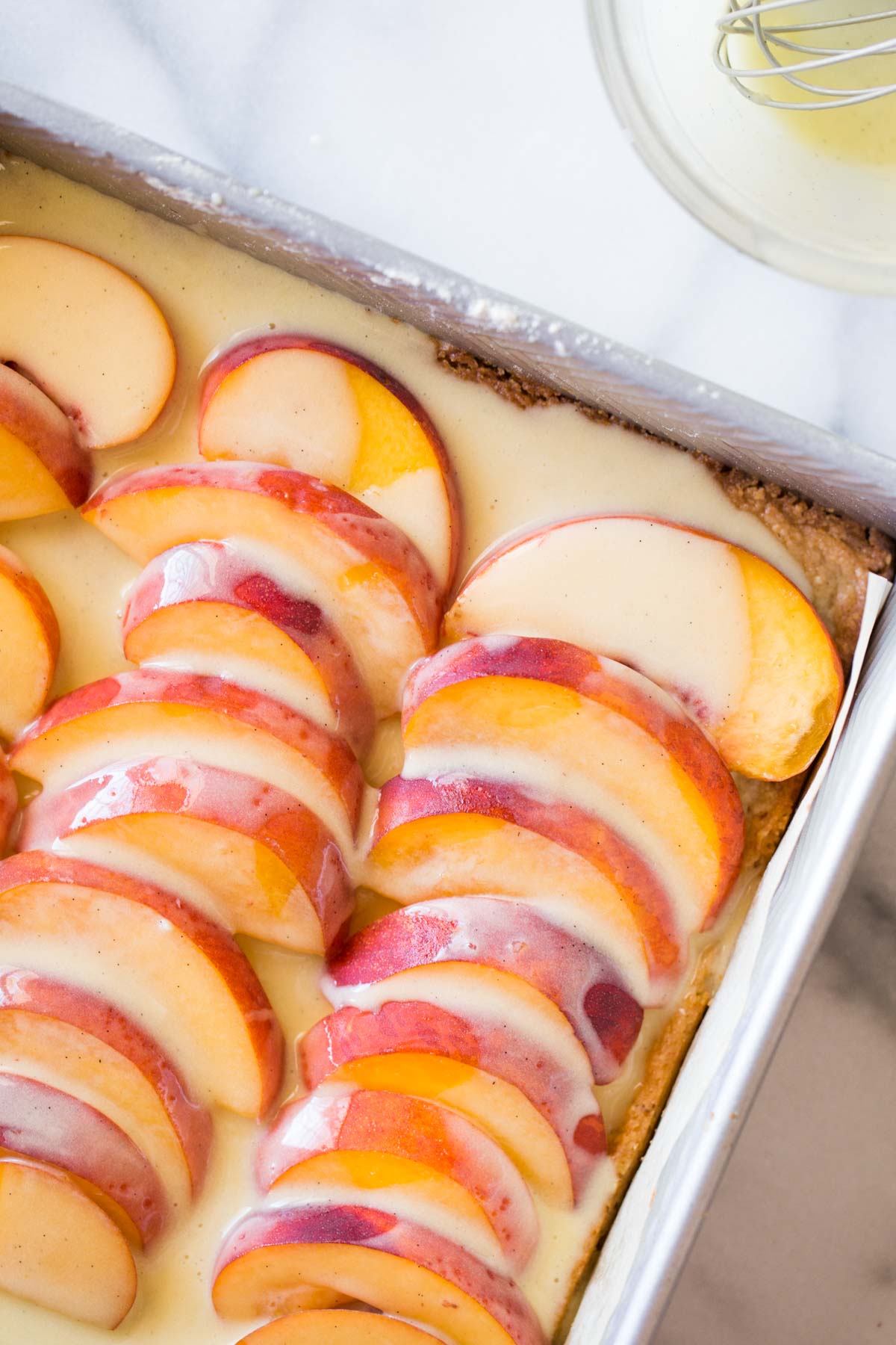 Peaches and Cream Shortbread Bars assembled in a baking dish prior to baking. 