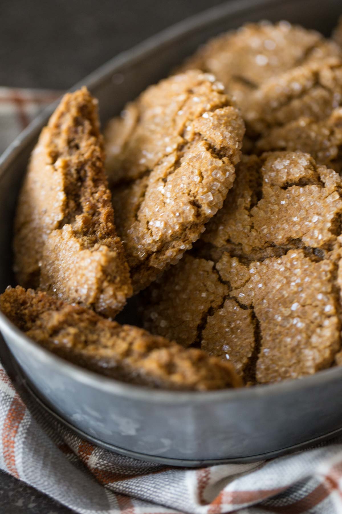 Peanut Butter Molasses Cookies in a galvanized bowl, with one of the cookies broken in half. 