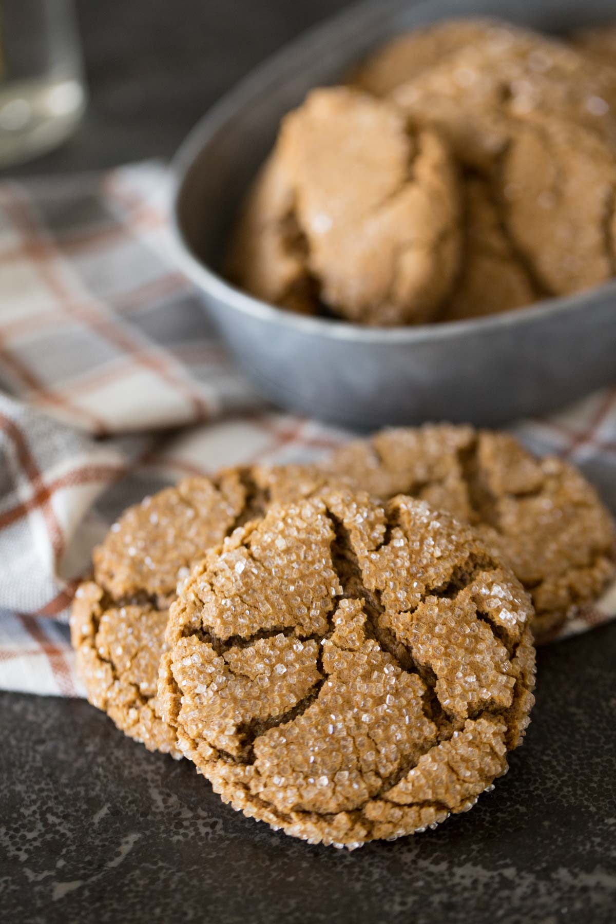 Three Peanut Butter Molasses Cookies with more cookies in a galvanized bowl in the background. 