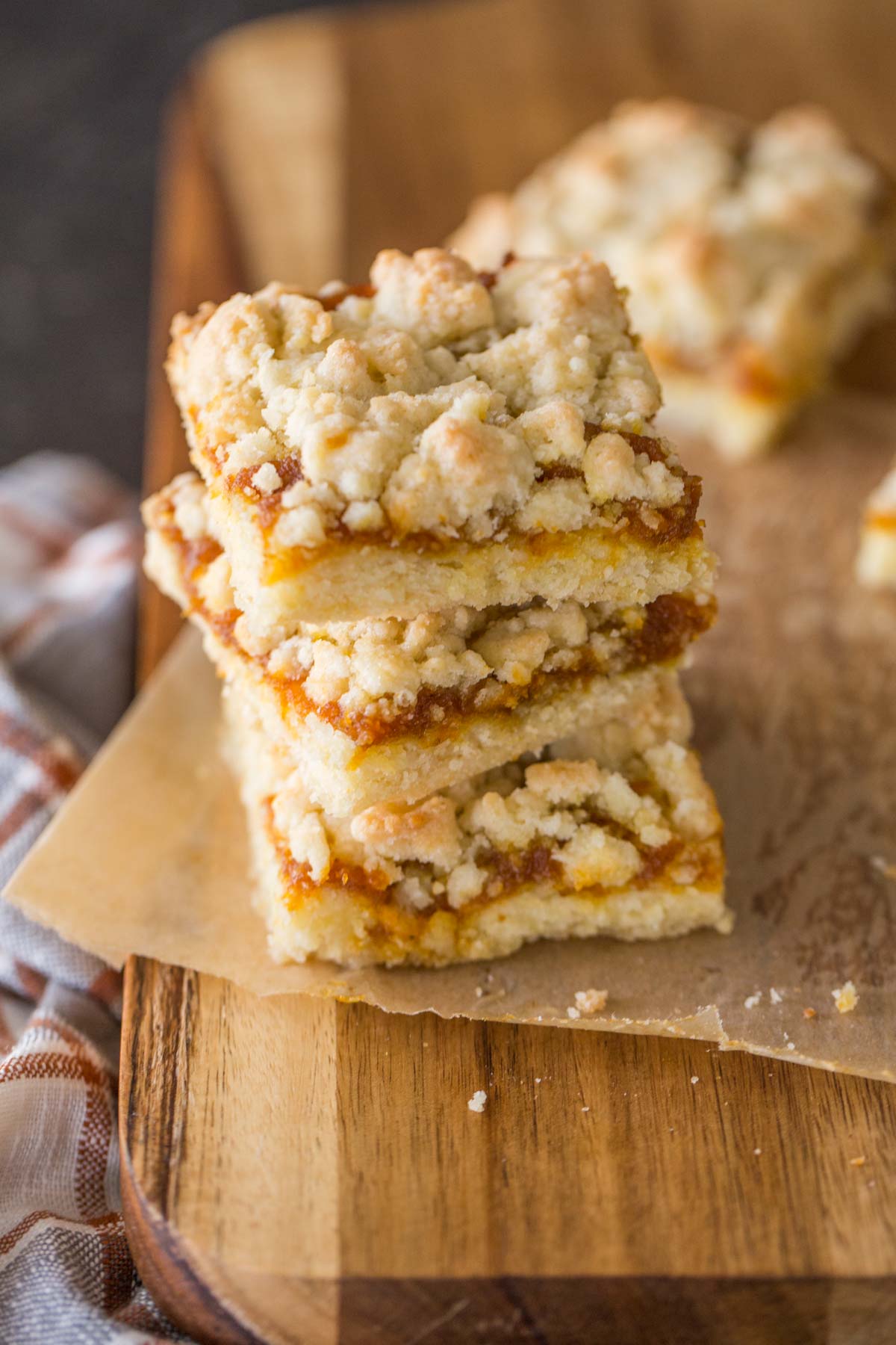 Three Pumpkin Butter Crumb Bars stacked on top of each other, sitting on a cutting board. 