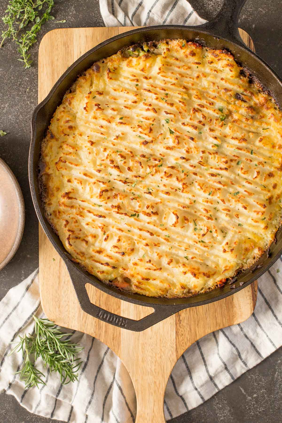 Easy Homemade Shepherd's Pie in a cast iron skillet, sitting on top of a wood cutting board. 