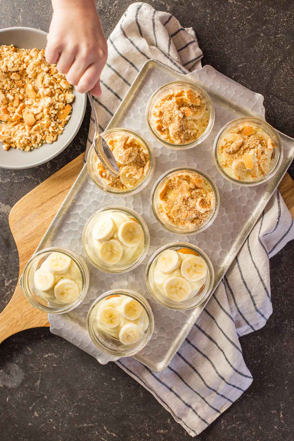 Spooning crushed Nilla wafers into individual banana pudding jars