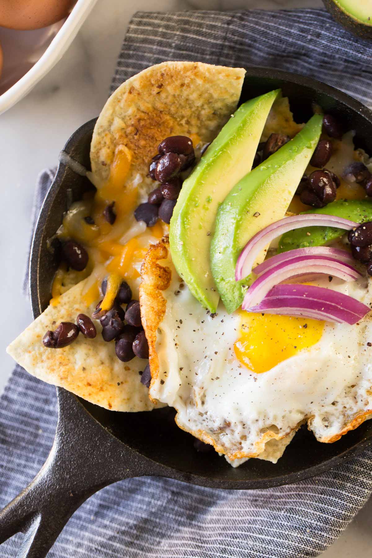 Breakfast Nacho Skillet topped with avocado slices and red onions. 