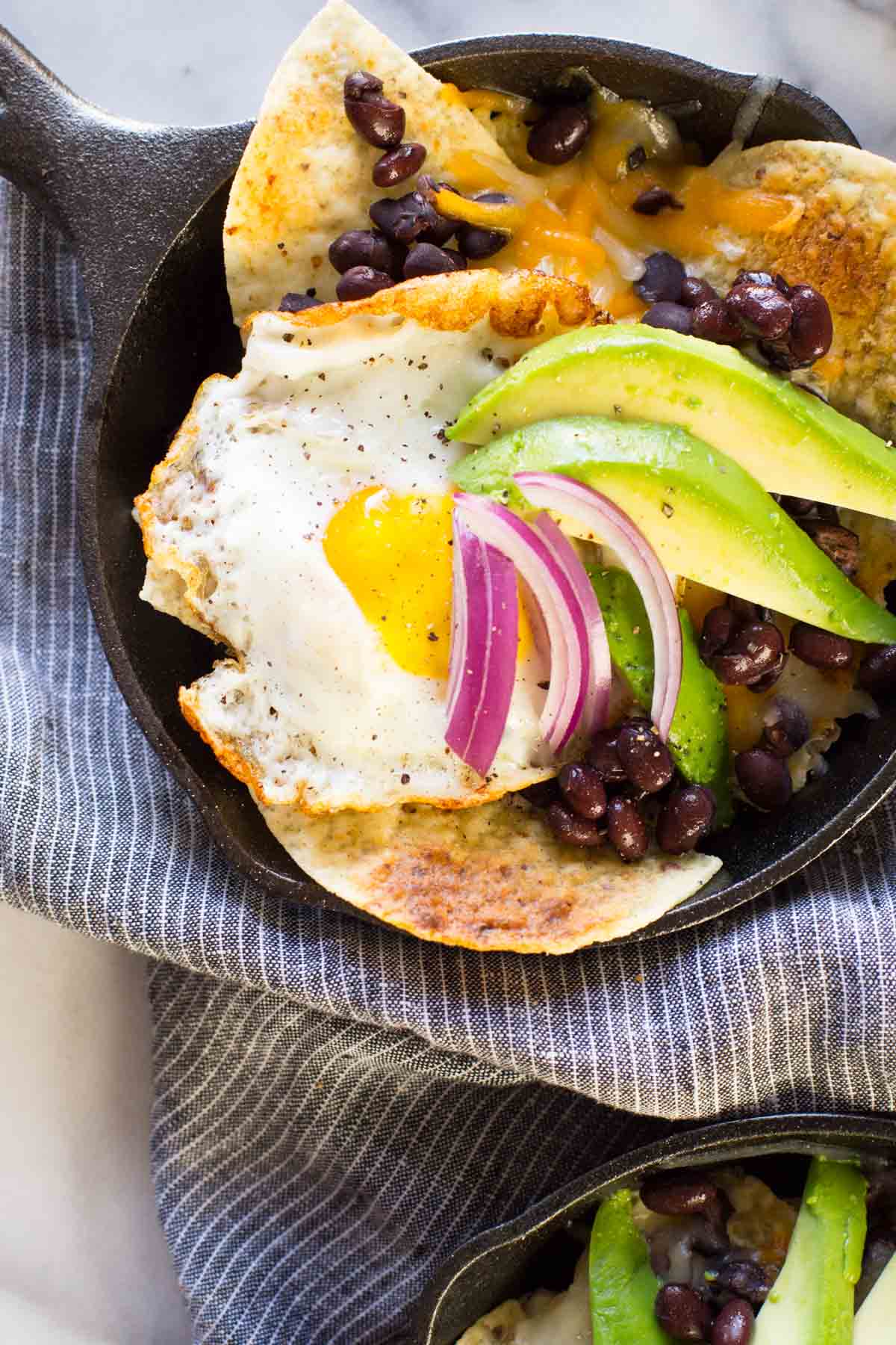 Breakfast Nacho Skillet topped with avocado slices and red onion.  