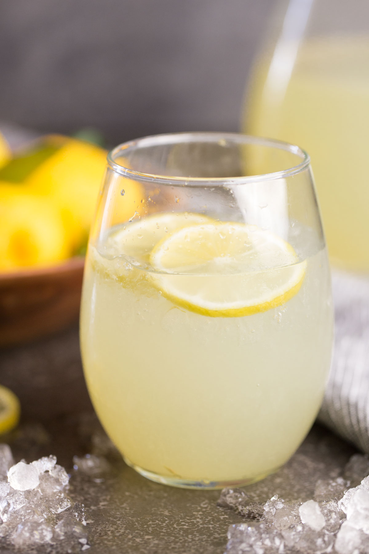 Close up front view of glass of lemonade with lemon slices and crushed ice. 