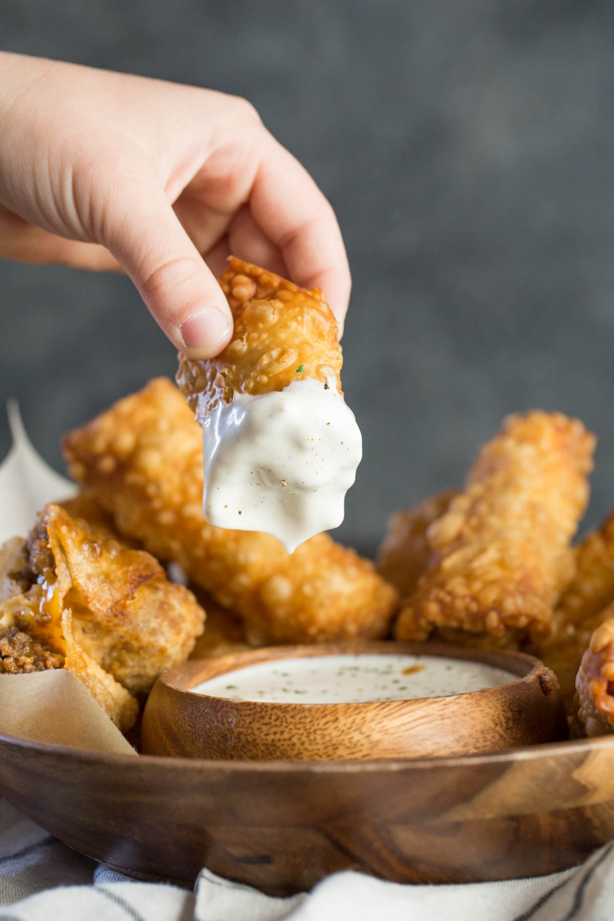 A half of a Fried Sloppy Joe Roll that has been dipped into a small bowl of ranch dip, that is surrounded by more Fried Sloppy Joe Rolls. 