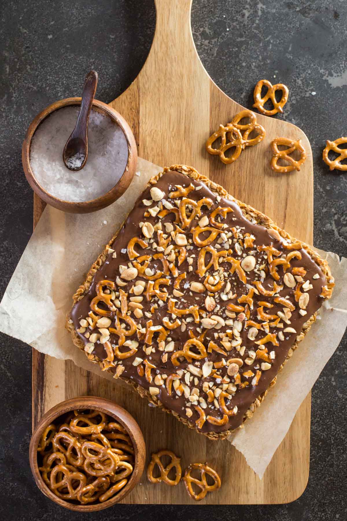 A slab of Oh Henry Bars uncut from a top down view, topped with peanuts and pretzels