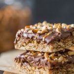 A side view of the chewy oat layer and chocolate peanut butter layer of two stacked Oh Henry Bars