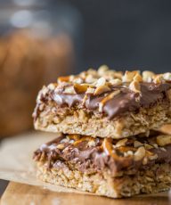 A side view of the chewy oat layer and chocolate peanut butter layer of two stacked Oh Henry Bars