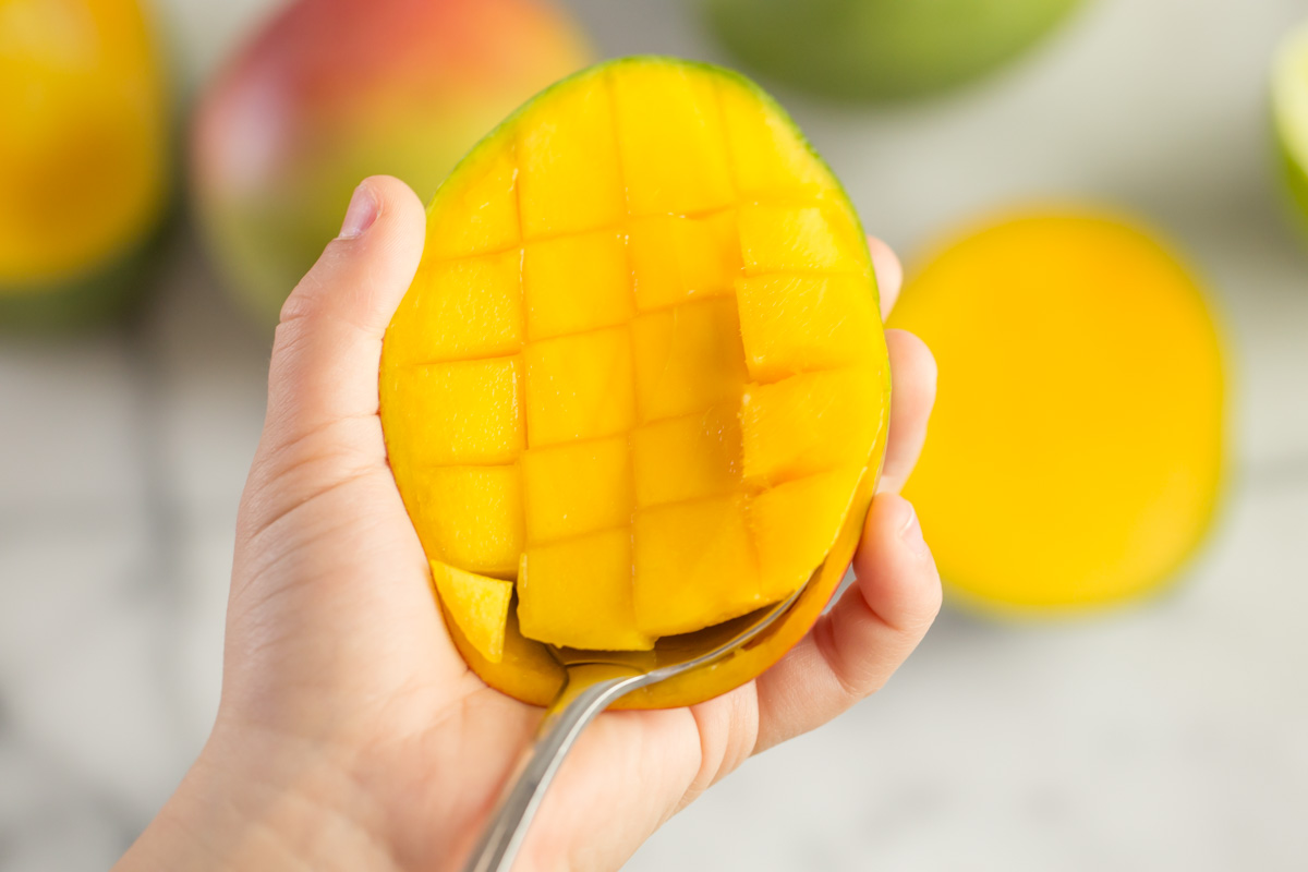 Step 5 of how to cut a mango - use a large spoon to detach the flesh from the skin and scoop out the cubes.