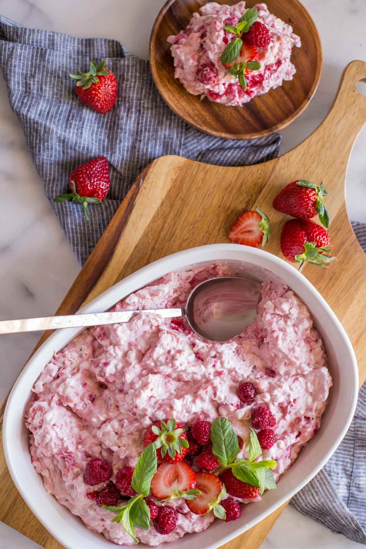 View from above of Very Berry Fluffy Salad in the dish as well as a single serving with fresh berries. 