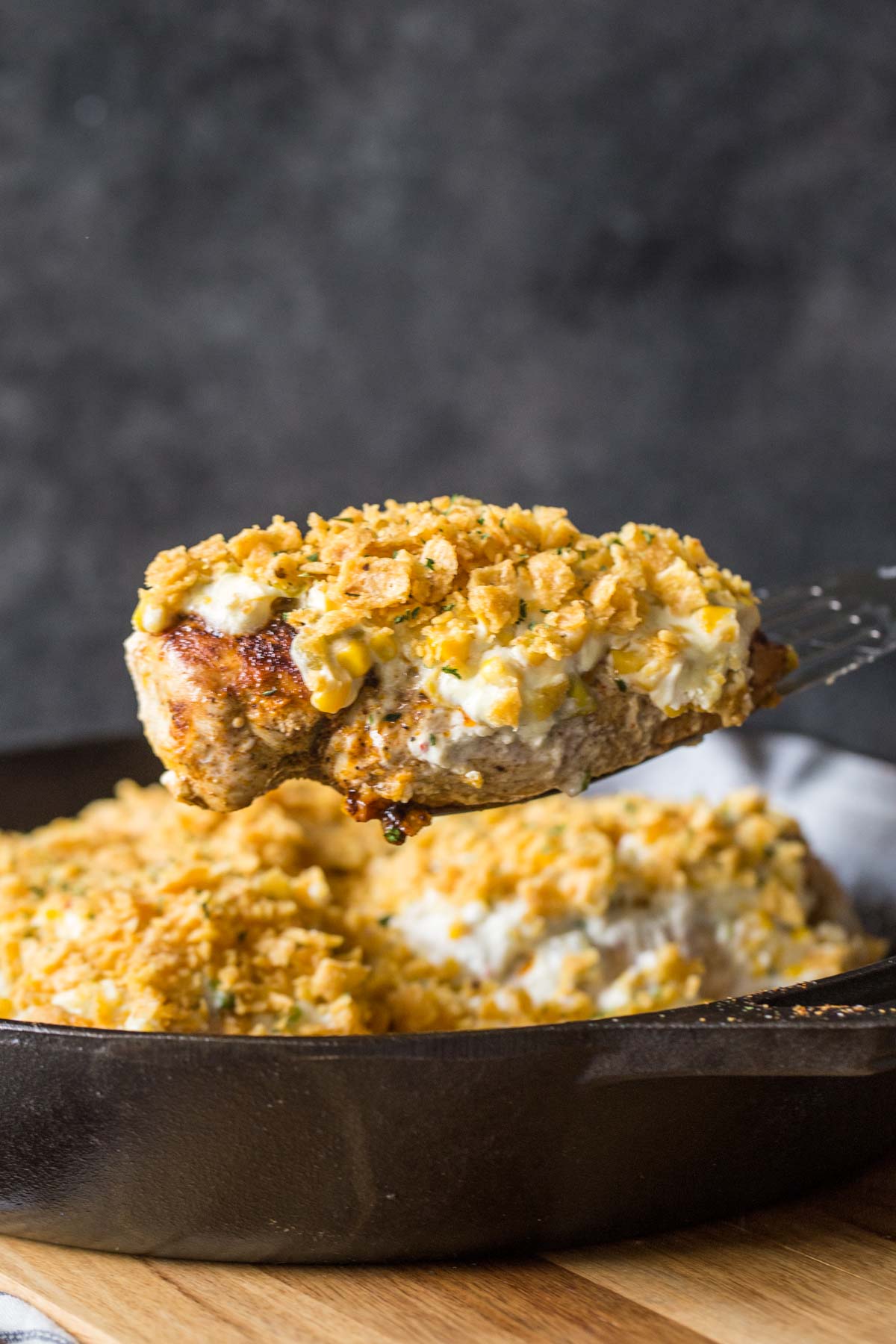 Creamy Cheesy Frito Chicken Skillet lifted out of cast iron skillet. 