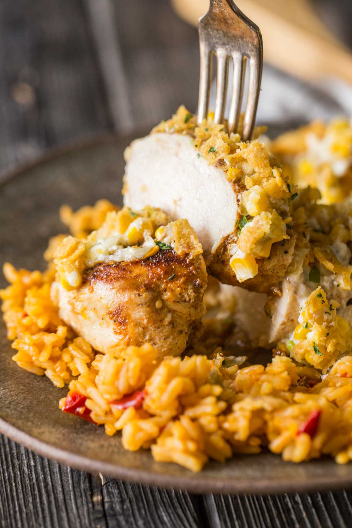 Slice of Creamy Cheesy Frito Chicken Skillet lifted off a plate with a fork. 