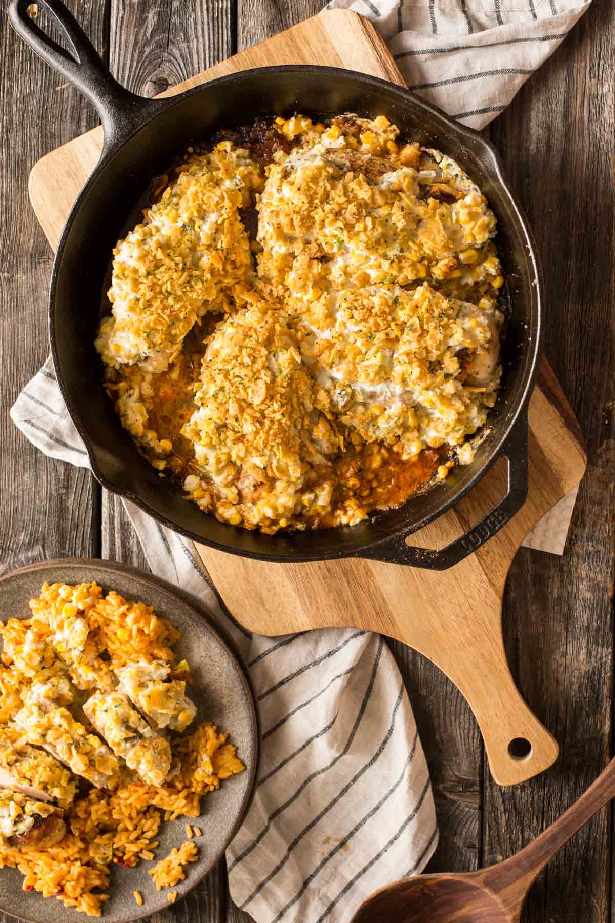Overhead shot of cast iron skillet with Creamy Cheesy Frito Chicken Skillet on a cutting board. 