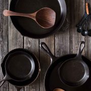 Various sizes of cast iron skillets on a wooden board.