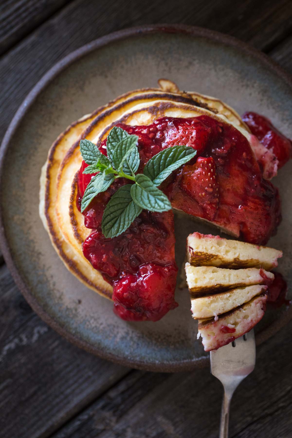 A top down view of a stack of Lemon Ricotta Pancakes with Fresh Berry Sauce. 