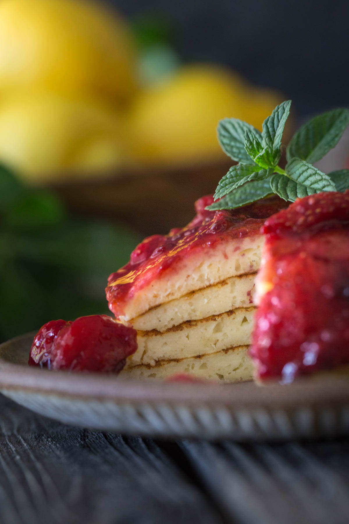 A plate of lemon ricotta pancakes with a bite cut out. 