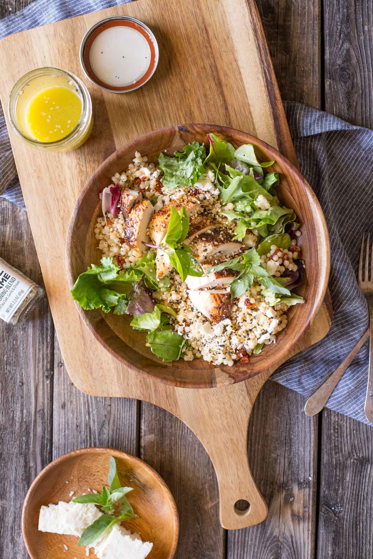 Israeli Couscous Salad with Honey Lemon Vinaigrette in a wooden bowl on a wooden cutting board.