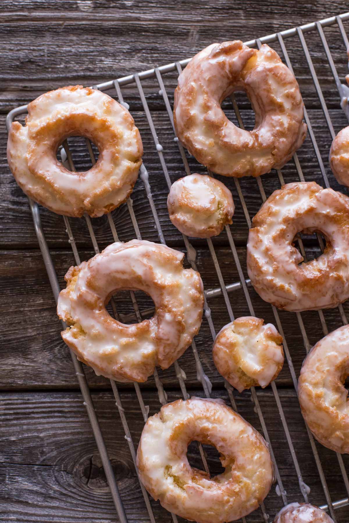 Overhead view of Old Fashioned Buttermilk Donuts on a cooking rack on a wooden background. 