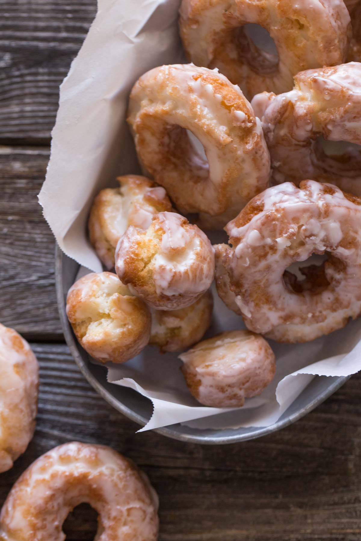 Top view of Old Fashioned Buttermilk Donuts with glaze in a metal basket. 