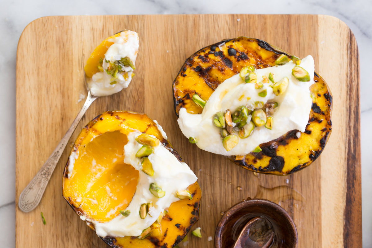 Grilled Mango With Honey Ricotta Whipped Cream with spoonful on a wooden board.