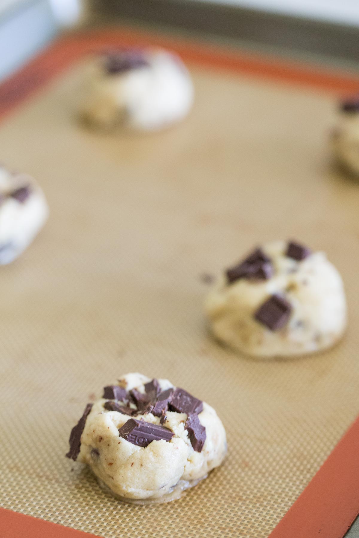 Toffee Almond Chocolate Chunk Cookie dough balls on a baking sheet. 