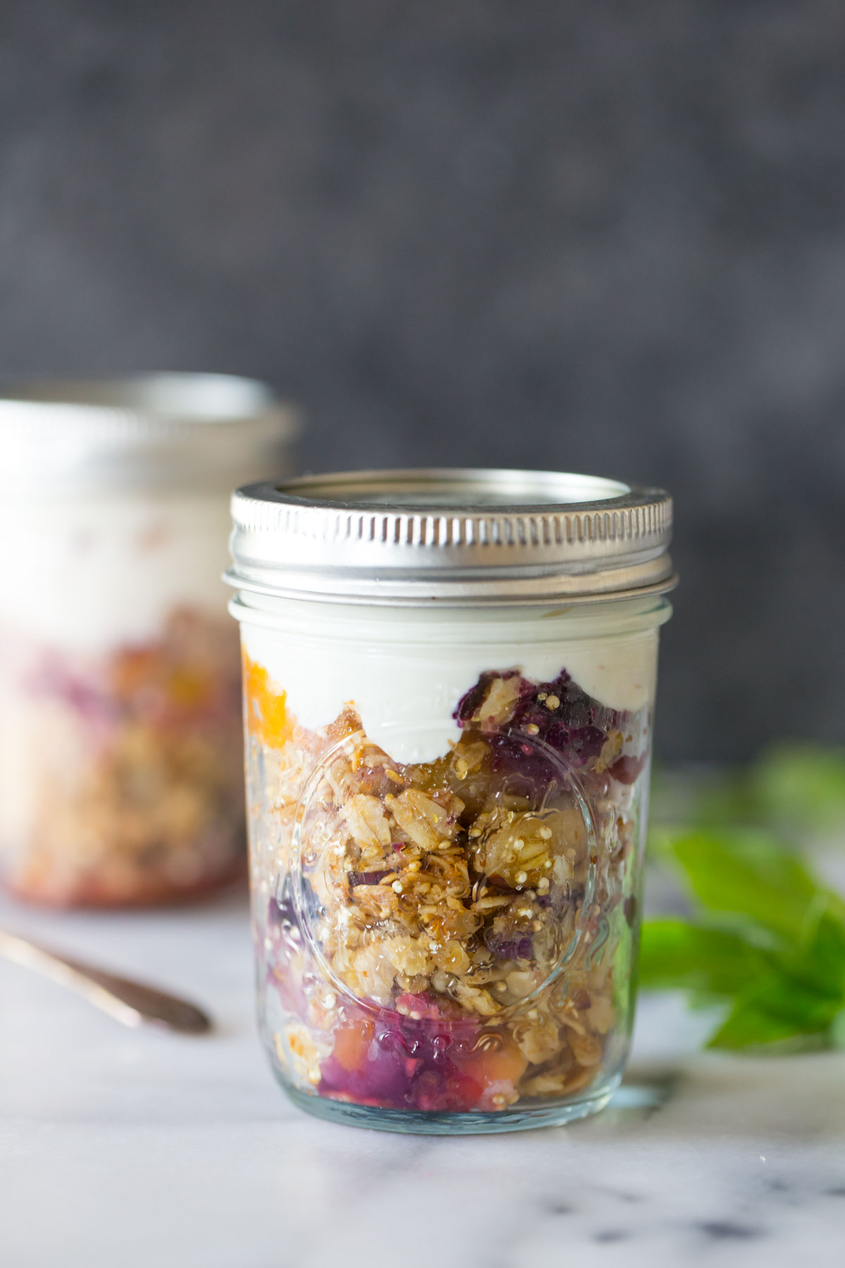 Mango Berry Breakfast Crisp in a mason jar topped with yogurt. 
