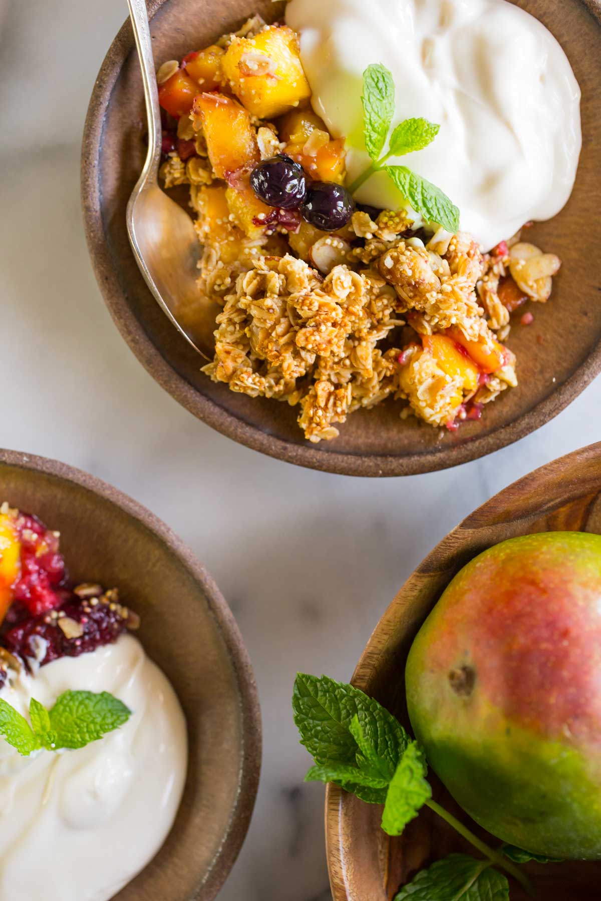 Mango Berry Breakfast Crisp in two serving bowls with yogurt. 