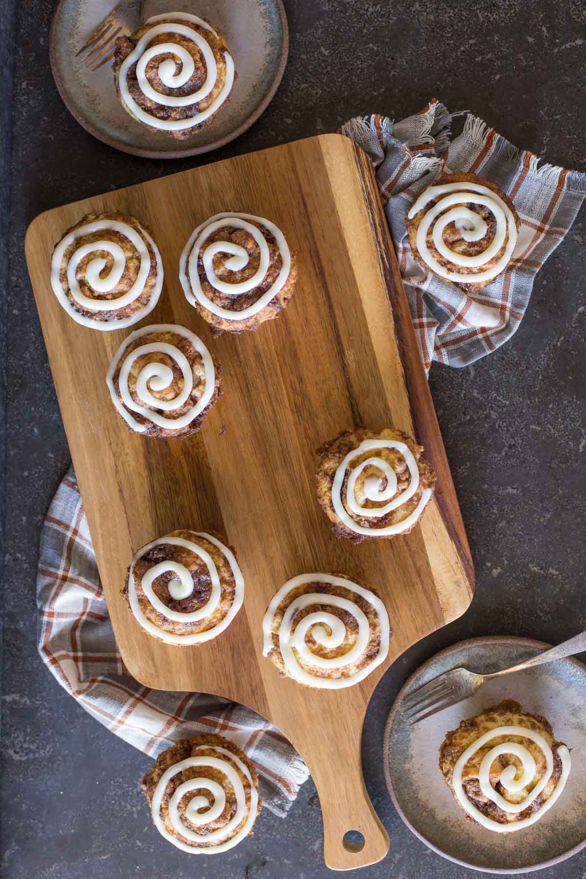 Cinnamon Roll Muffins with a cream cheese icing swirl on a wooden cutting board.
