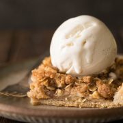 A close up view a piece of Dutch Apple Slab Pie with a scoop of vanilla ice cream on top.
