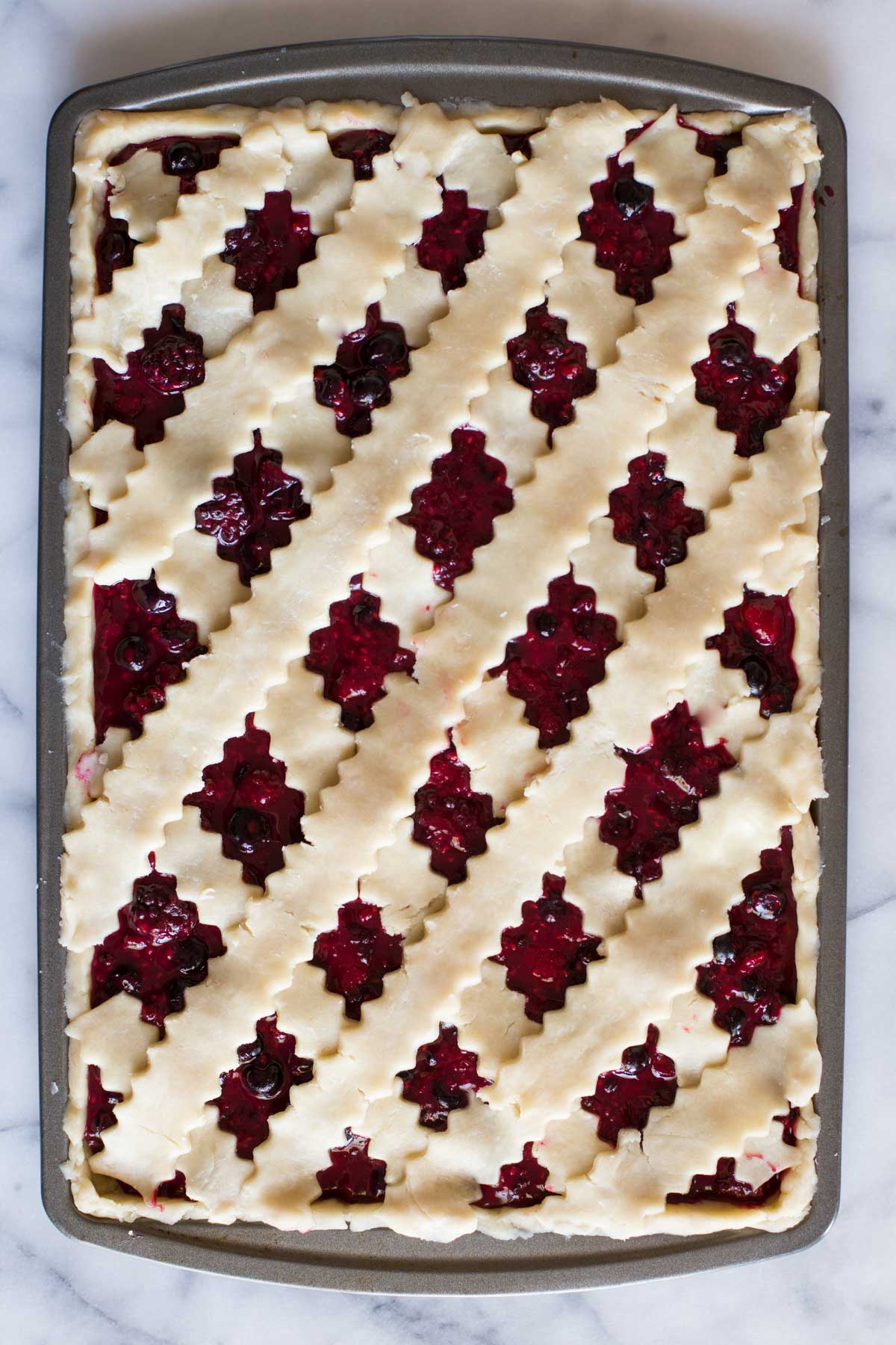 Triple Berry Slab Pie topped with a lattice crust ready to be baked. 