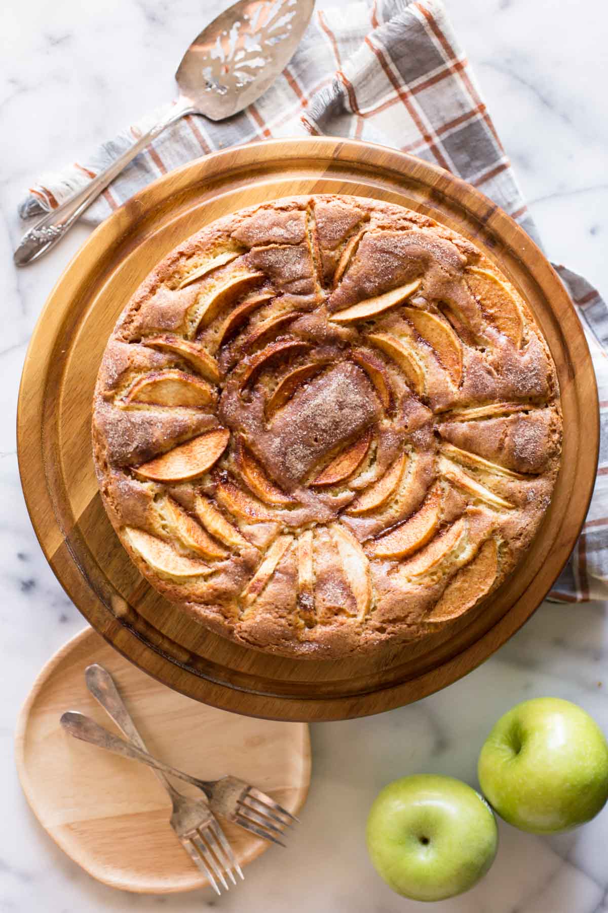 Apple Cider Cake on a wooden cake stand on a white marble board. 