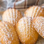 Close up view of Lemon Vanilla Madeleines with a dusting of powdered sugar.