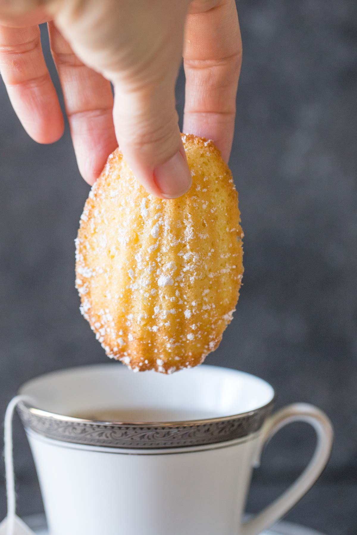 Lemon Vanilla Madeleine about to dip into a cup of tea. 