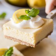 Close up view of the Best Creamy Lemon Bars on a marble slab topped with lemon slices, fresh mint and whipped cream.