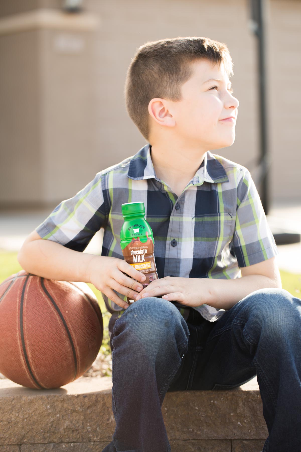 Boy sitting by a basketball with Shamrock Farms chocolate milk in his hand. 