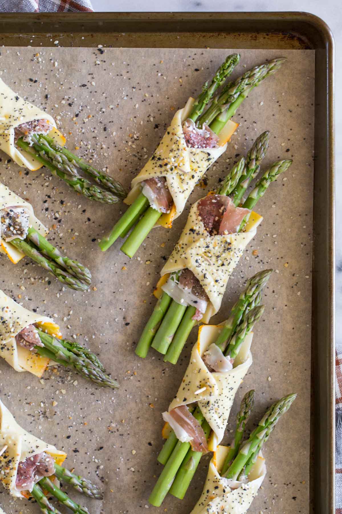 Overhead view of uncooked Puff Pastry Asparagus Bundles on a baking sheet. 