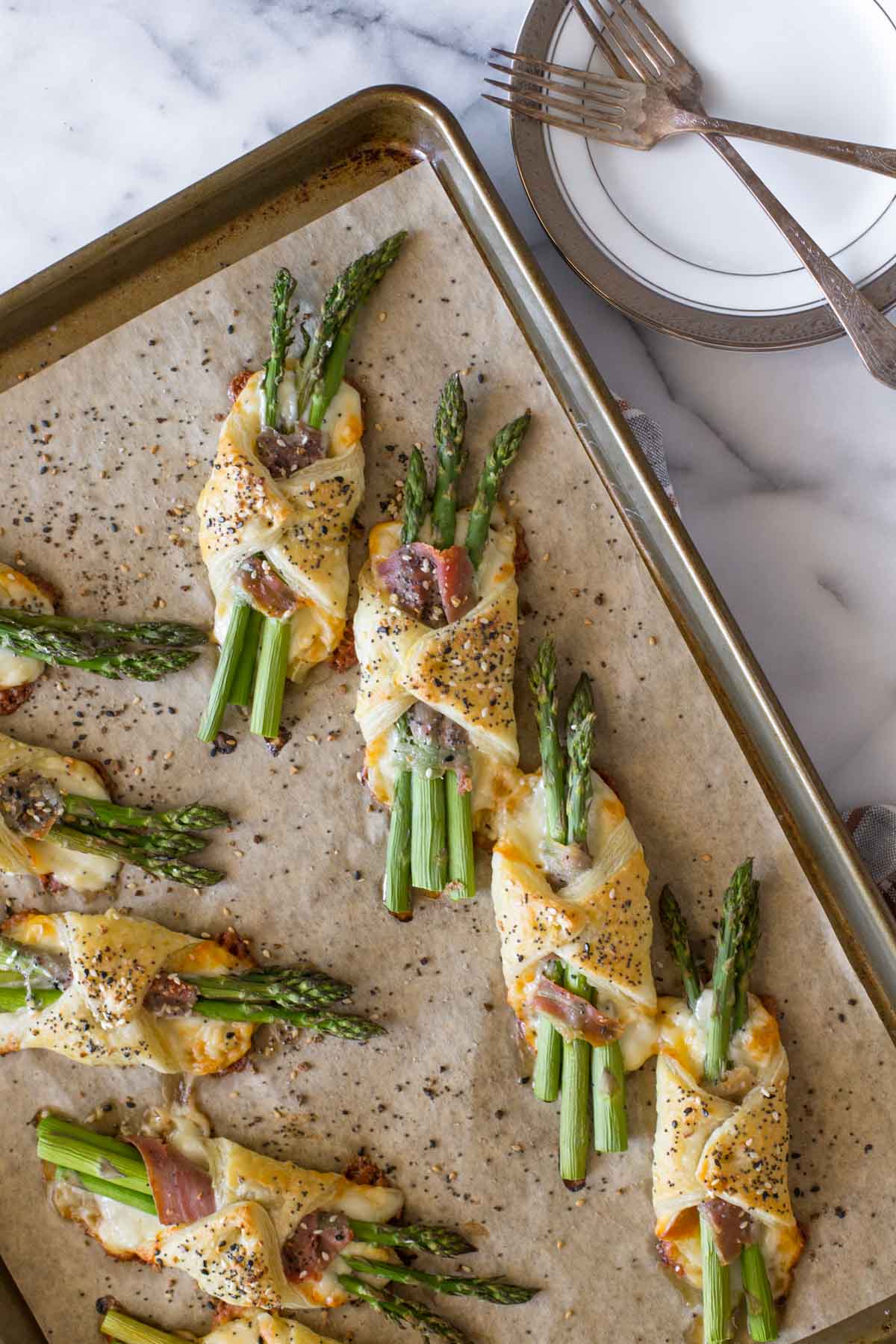 Overhead view of Puff Pastry Asparagus bundles on a baking sheet. 