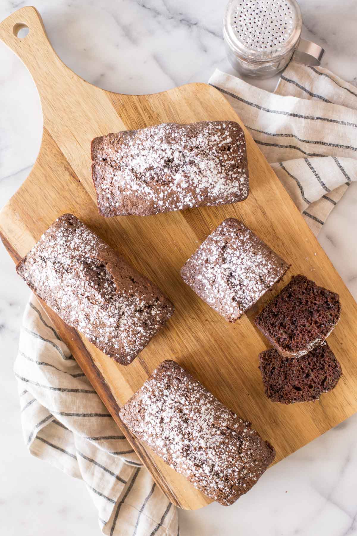 Overhead view of Chocolate Zucchini Bread dusted with powdered sugar on a wooden cutting board. 