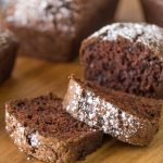 Slices of Chocolate Zucchini Bread on a wooden cutting board.