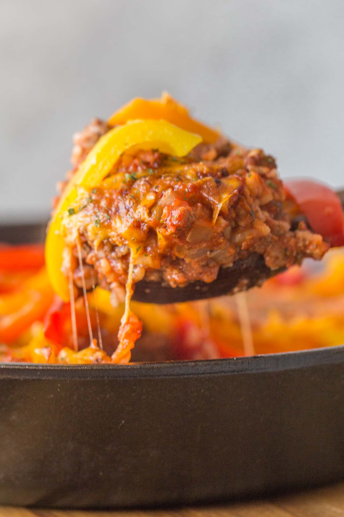 Close up shot of Unstuffed Pepper Skillet being served out of the skillet with melty cheese. 