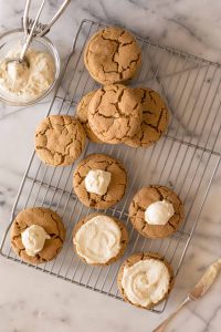 Bakery Style Molasses Cookies on a white marble board in the process of frosting.