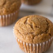 Close up view of the top of a Cinnamon Applesauce Muffin on a white background.