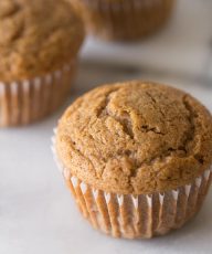 Close up view of the top of a Cinnamon Applesauce Muffin on a white background.