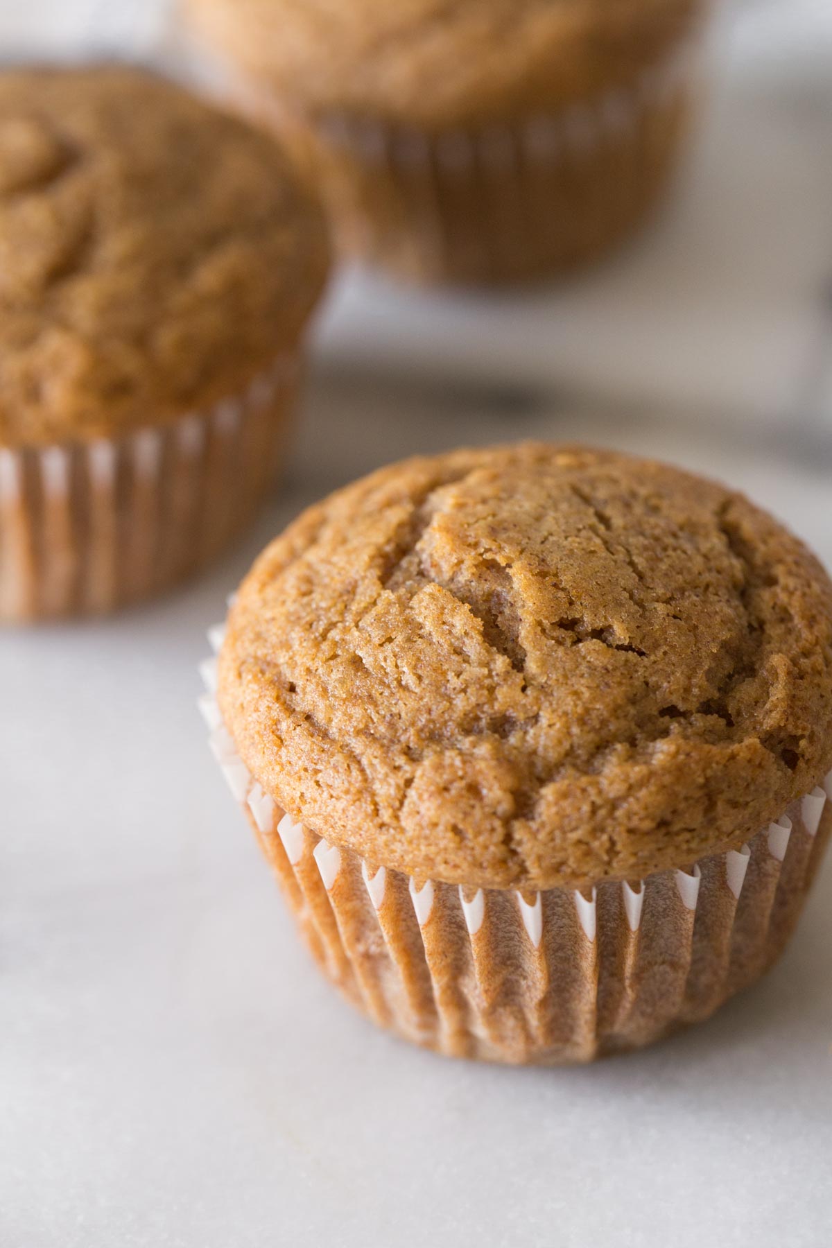 A close up view of the top of a Cinnamon Applesauce Muffin on a white background. 