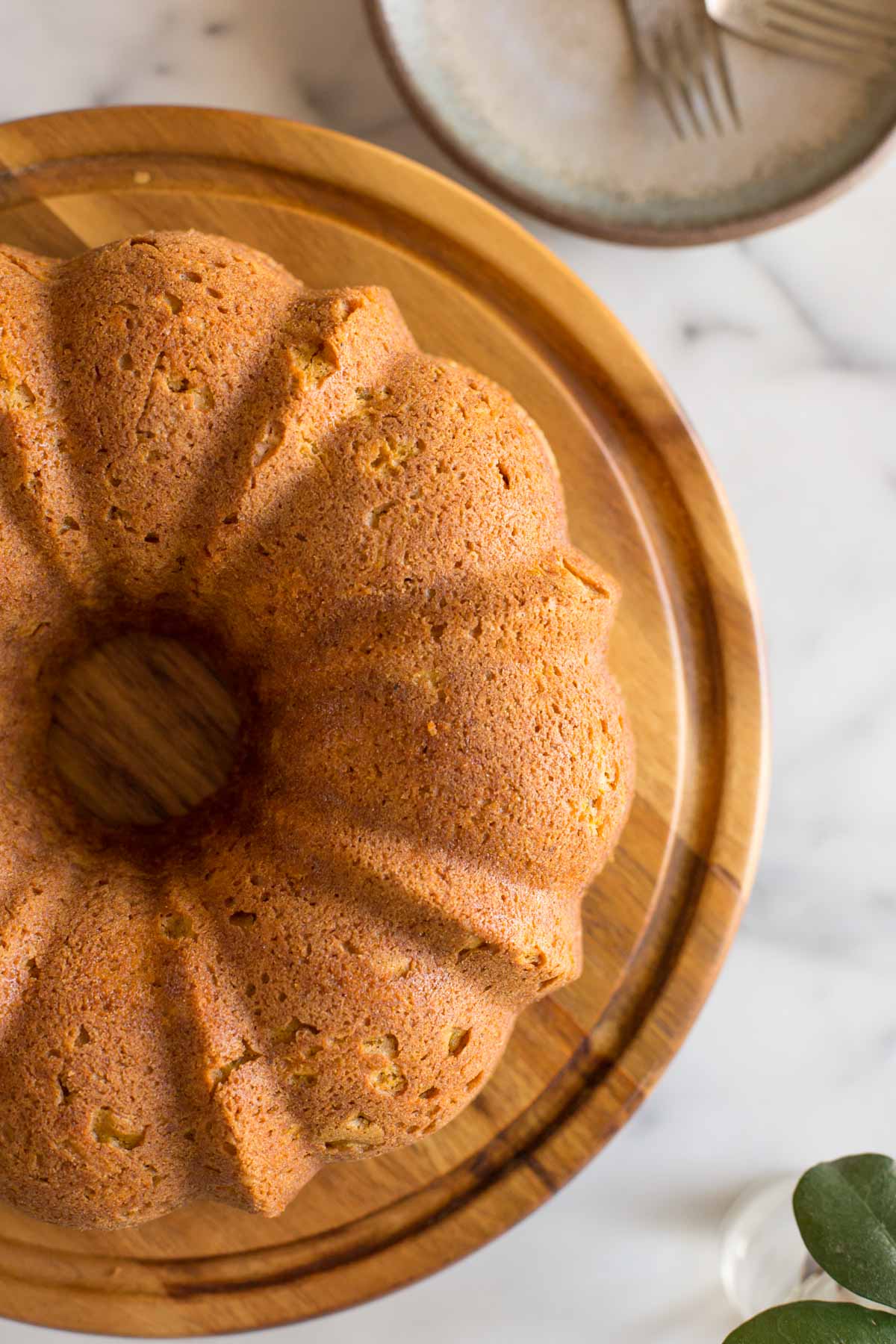 Overhead view of Apple Pumpkin Cake on a cake stand. with a white marble background. 