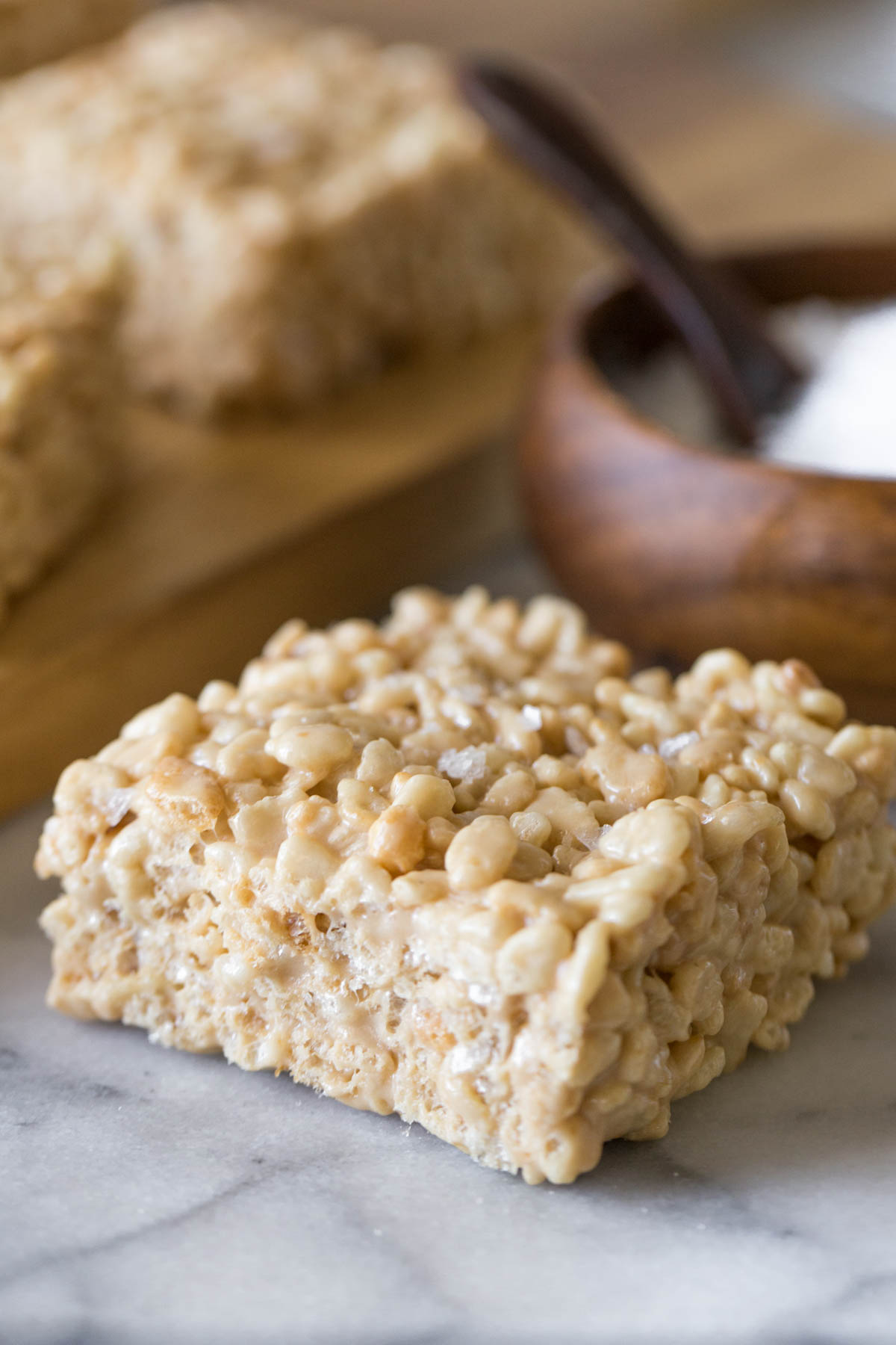 Close up view of Salted Caramel Rice Krispie Treats with bowl of sea salt in the background. 