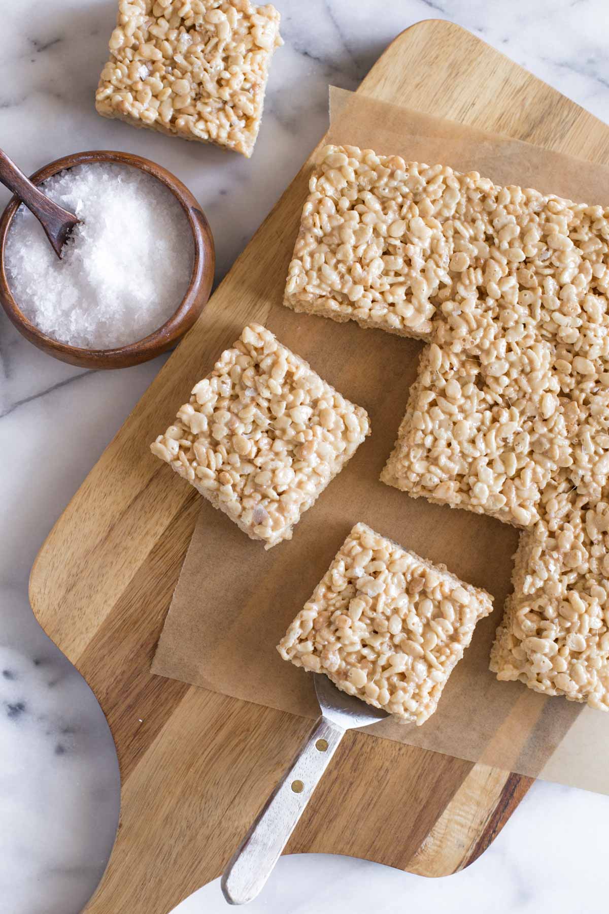 Overhead view of Salted Caramel Rice Krispie Treats on a wooden cutting board. 