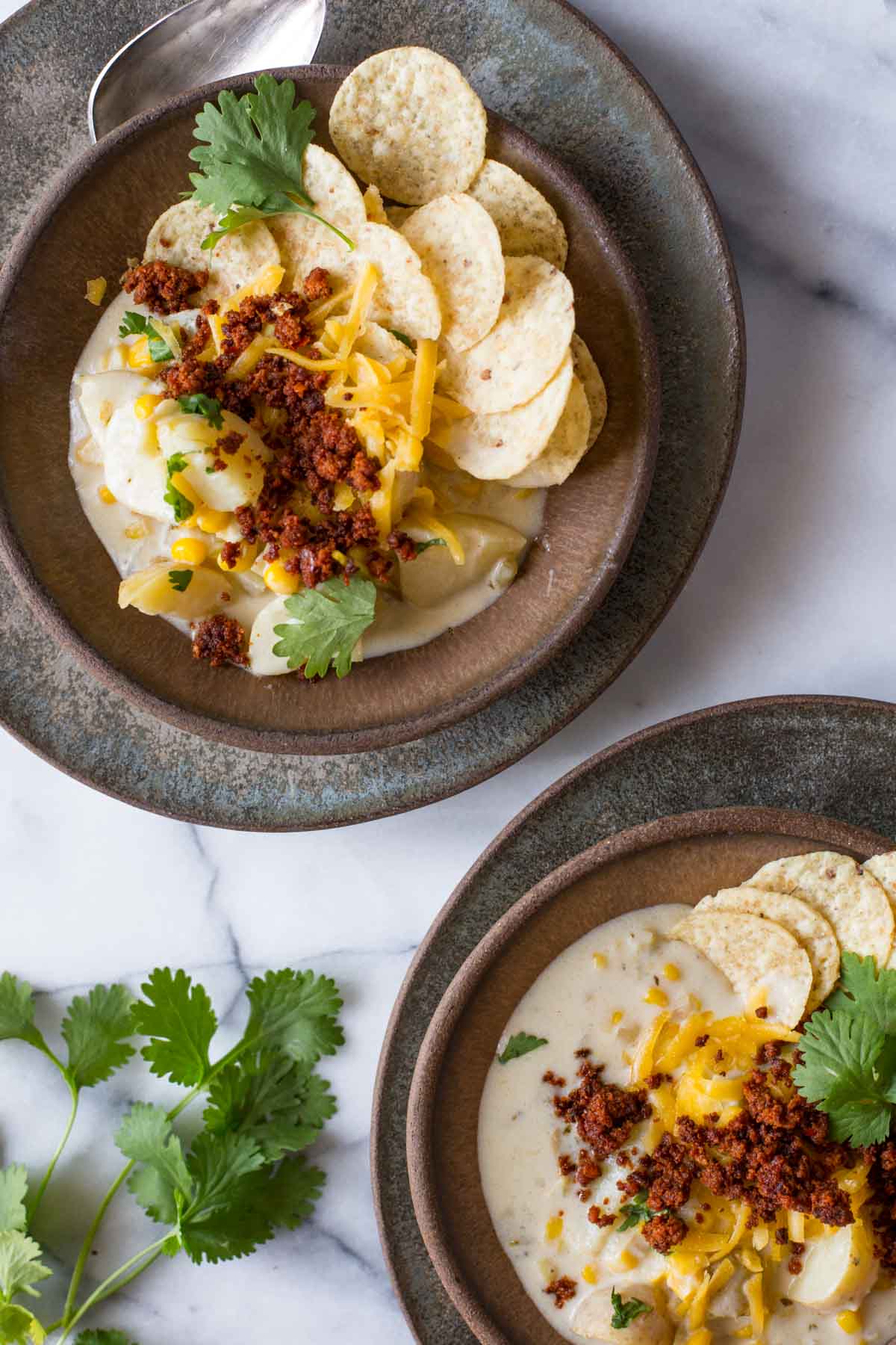 Overhead view of Creamy Corn Chowder With Chorizo in two brown bowls. 